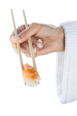 Japanese sushi with shrimp on sticks in female hand isolated on white background. Healthy diet.