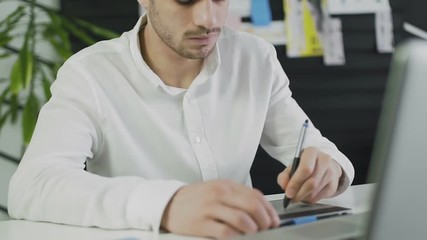 Casual male designer using graphics tablet in a bright office