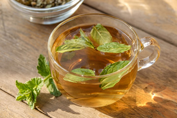 Tasty herbal tea in glass teapot on old wooden table