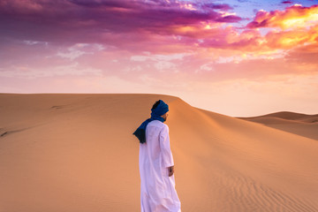 Fototapeta na wymiar Berber man wearing traditional tuareg clothes in the Sahara Desert at dawn, Merzouga, Morocco