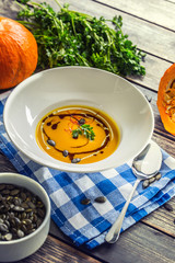 Pumpkin cream soup with seeds and parsley on kitchen table