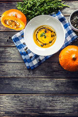 Pumpkin cream soup with seeds and parsley on kitchen table - Top of view