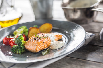 Roasted salmon fillet broccoli tomatoes and fried potatoes with dill cream sauce