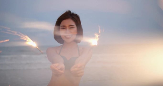 Beautiful asian young girls playing firework slow motion wearing string bikini sexy butt tropical vacation travel holidays. 4K resolution and slow motion.