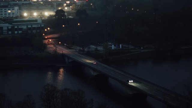 Cars driving over a bridge at night. Street lamps are reflecting in the water.