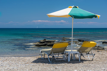 Sun beds, lounge chairs and an umbrella on the beach, on the seashore.