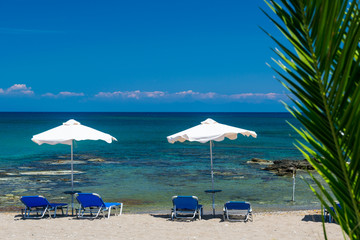 Sun beds, lounge chairs and an umbrella on the beach, on the seashore.