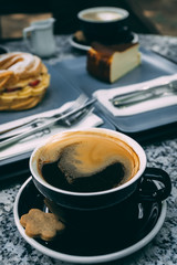 Fresh served coffee cup with dessert in the background.