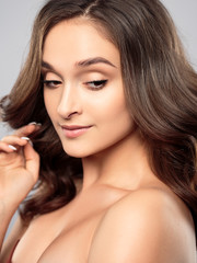 Brunette girl with healthy curly hair and natural make up . Beautiful model woman with wavy hairstyle .Care and beauty