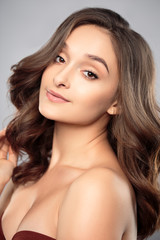 Obraz premium Brunette girl with healthy curly hair and natural make up . Beautiful model woman with wavy hairstyle .Care and beauty