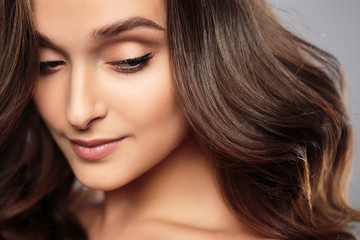 Fototapeta premium Brunetka dziewczyna z zdrowe włosy kręcone i naturalny makijaż. Piękny model kobiety z falowaną fryzurą. Pielęgnacja i uroda