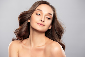 Naklejka premium Brunette girl with healthy curly hair and natural make up . Beautiful model woman with wavy hairstyle .Care and beauty