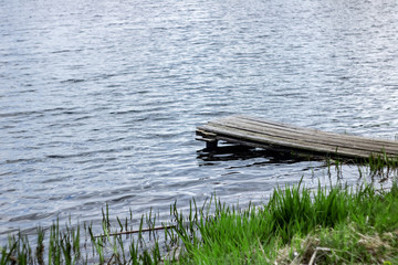 Wooden laying on the river at the shore with green grass