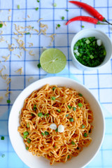Dried instant noodle in white ceramic bowl on tablecloth