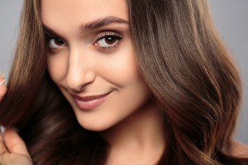 Obraz premium Brunetka dziewczyna z zdrowe włosy kręcone i naturalny makijaż. Piękny model kobiety z falowaną fryzurą. Pielęgnacja i uroda
