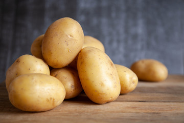 Pile of potatoes on old wooden table. Dark background.