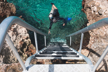 Scuba diver floating in water next to staircase in San Andres, Colombia