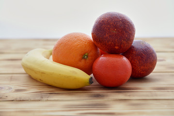 orange, red orange and tangerines lie on a wooden board