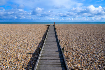 long straight wooden pathway on pebble beach