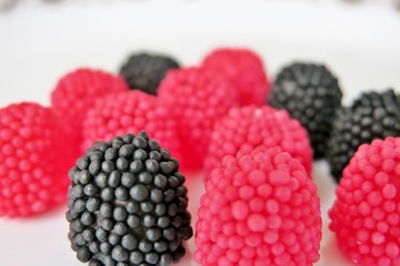 jelly candies in the form of raspberries, red and black on a white background