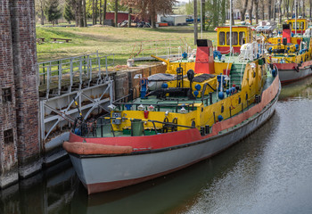 Fototapeta na wymiar Sluice, water gate with colorful tugboats parked along the berth in Sobieszewo in Poland.