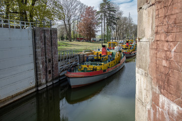 Sluice, water gate with colorful tugboats parked along the berth in Sobieszewo in Poland.