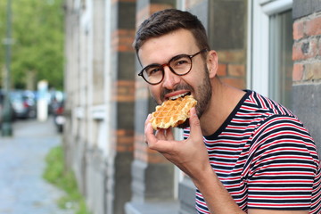 Cute guy eating a waffle in Brussels, Belgium
