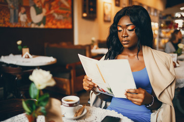 Elegant black woman sitting in a cafe. Businesswoman drinking a coffee