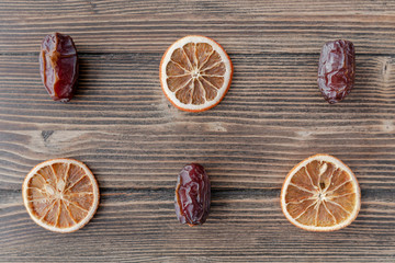 Orange chips, dried orange slices, and date fruits on wooden backgrond. Horizontal image. Top view, flat lay. Copy space