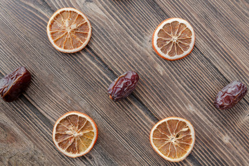 Fototapeta na wymiar Orange chips, dried orange slices, and date fruits on wooden backgrond. Horizontal image. Top view, flat lay. Copy space