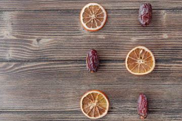 Orange chips, dried orange slices, and date fruits on wooden backgrond. Horizontal image. Top view, flat lay. Copy space