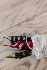 Colorful ancient Georgian national sweet churchkhela, different colours, in white cooking paper. vertical image. Wooden background.  Top view. Copy space.