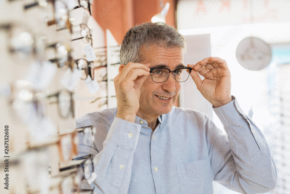 Sticker middle aged man choosing eye glasses in optic store