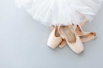Ballet pointe shoes and white tutu skirt on gray background. Concept of dance, spring, ballet school, ballerinas clothes, stuff and things. Top view, flat lay. Copy space. - obrazy, fototapety, plakaty