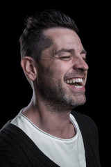 Obraz premium Side studio portrait of a smiling man with closed eyes. Isolated on black background. Vertical.