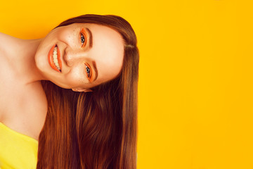 Beautiful girl with shiny brown straight long hair. Keratin straightening . Treatment, care and spa. Woman with orange makeup with freckles. Smile girl near empty copy space looking at the camera