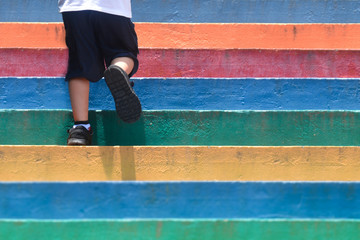 Lower part of a boy in casual shoe walking up outdoor colorful stair,children lifestyle successful...