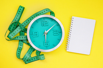 Alarm clock with measuring tape. Weight loss or diet concept. notepad for writing. space for text