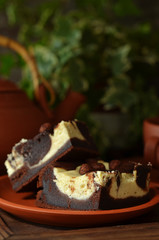 Brownie with cheesecake on a rustic plate