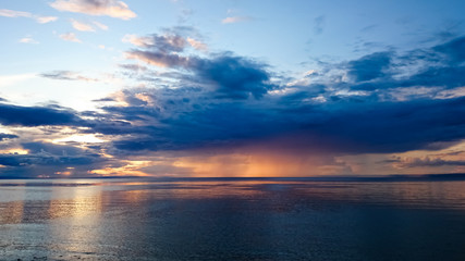 Naklejka na ściany i meble Sunset on Lake Baikal. Evening, rain, clouds, sun. Dramatic sky. Atmospheric landscape. The shore of Lake Baikal. Russia.
