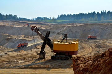 View of the open pit mining. A large number of excavators and mining trucks work in a quarry for transporting sand to a crushing plant - Image © MaxSafaniuk