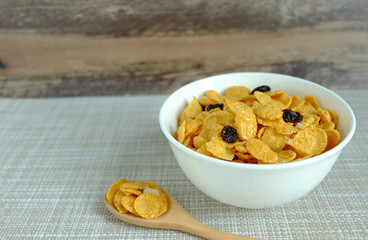 Corn flakes in white bowl on wood background
