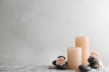Composition of burning candles, spa stones and flowers on table. Space for text