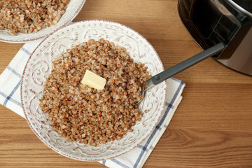 Delicious buckwheat and modern multi cooker on wooden table, above view