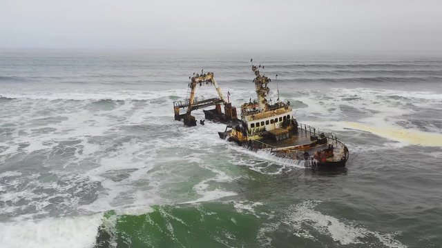 Dramatic aerial over a spooky shipwreck grounded fishing trawler along the Skeleton Coast of Namibia.