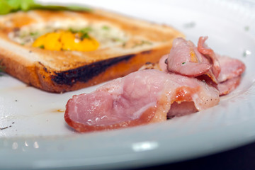 slices of fried bacon with croutons and scrambled eggs on a white plate