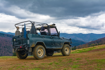 Extreme tourist trip to the top of the mountain on the dirt and stones on a special off-road Jeep to see the beauty of the mountains and forests on the horizon on top of the world