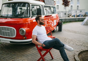 Handsome hipster man in sunglasses walking along the street. White t-shirt.