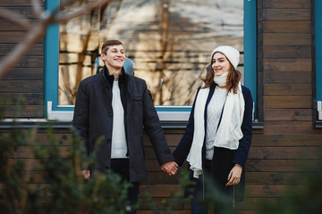 Pretty couple walking in a winter city. Man and woman standing near building;