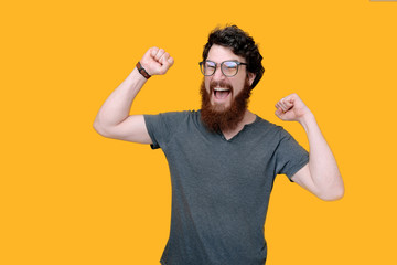 Winner guy, photo of beaded man celebrating with rised hands, ovr yellow background